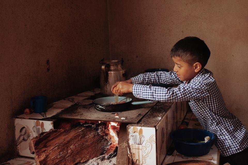 TomÃ¡s, nine, making eggs with tomatoes at his home in Quiche district, Guatemala