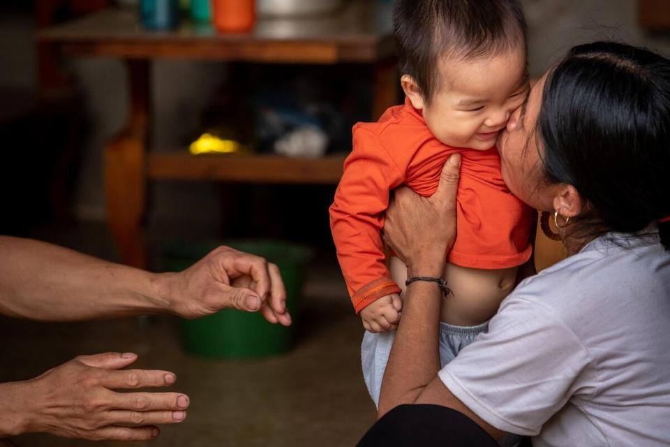  One-year-old Tuan Luong plays with his father Tuan Linh and mother Thi Hoa, 43, at their house in An Luong Village, Van Chan District, Yen Bai Province, Vietnam.