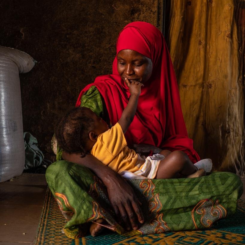 Hafsat, 30, holding her 18-month-old daughter Saratou, inside their home in Jigawa State, Nigeria.
