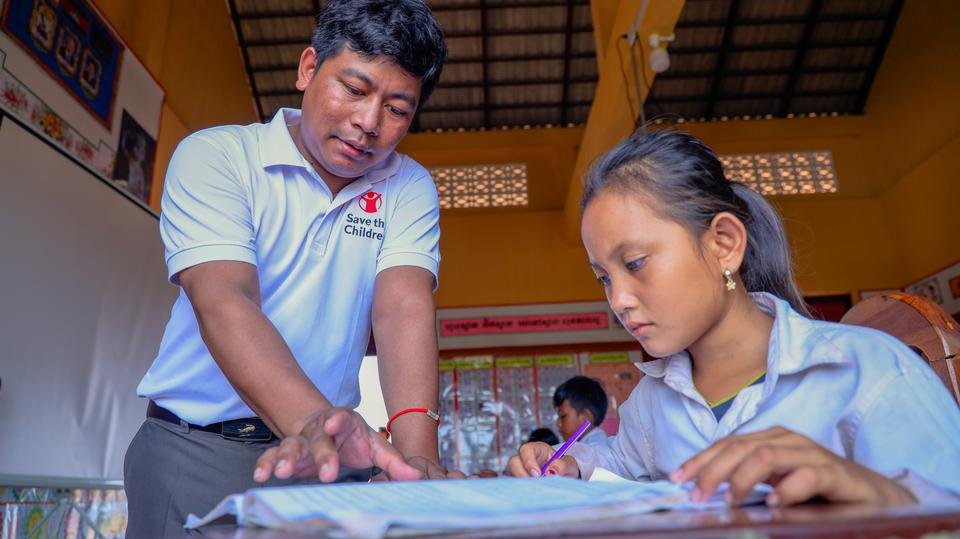 Sreykheth's teacher Saeu helping her with reading, Cambodia