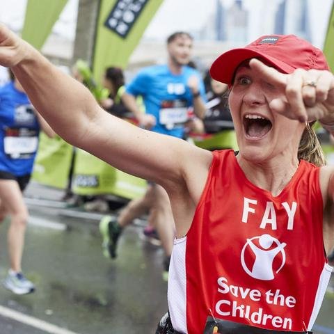 Fay, a Shelter For Kids supporter, smiling and pointing towards the camera as she's running past during the London Marathon