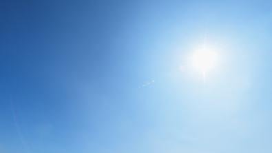 A blue sky with no clouds and the sunshining down in the top right corner.