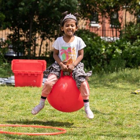 Alifa, 3, plays on a space hopper at an Ambition Aspire Achieve holiday play session in Tower Hamlets