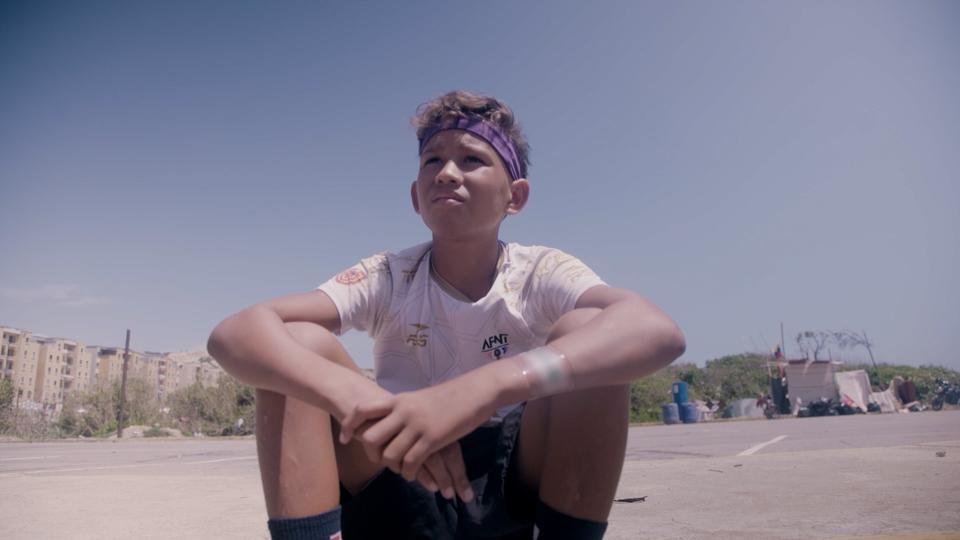 Carlos*, a child affected by the 2026 Venezuela earthquakes, sits outside one of Shelter For Kids's safe spaces. 