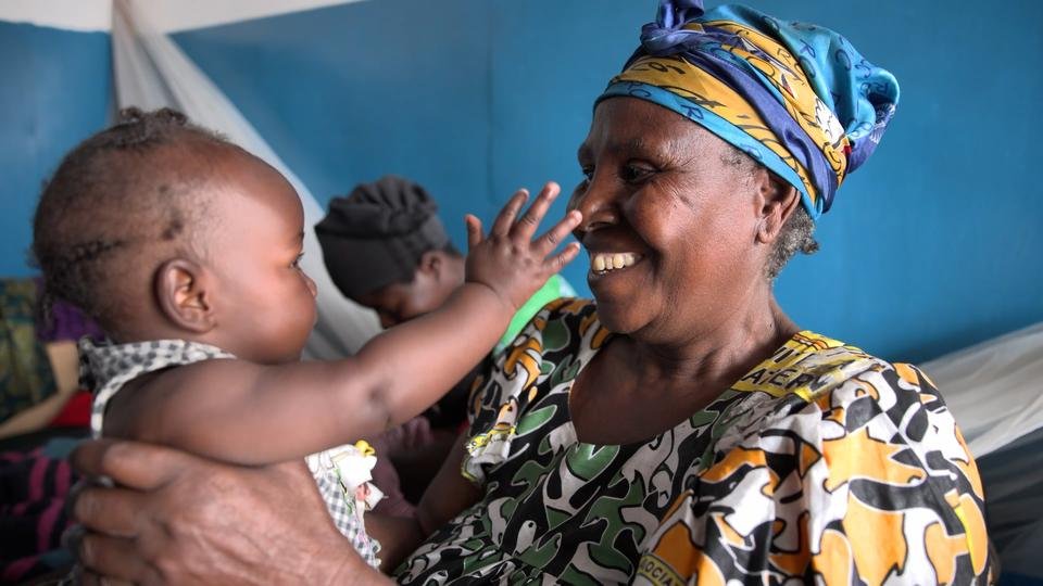 Kavira*, smiles as she holds up her granddaughter, Solange*, 5 months, in the clinic