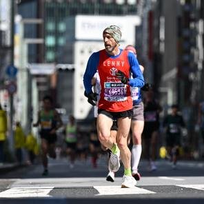 Lenny running down city street in Tokyo wearing a Shelter For Kids charity vest for the 2024 Marathon