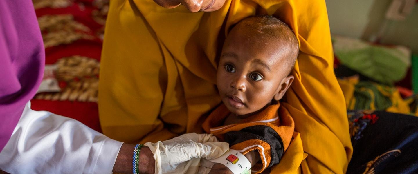 Nurse Fartoun* measures Guled's* arm with a MUAC band to assess his level of malnutrition