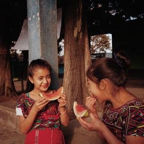 Cousins Anabely, 11, and Maria Elena, 12, eating fruit at school in Quiche district, Guatemala