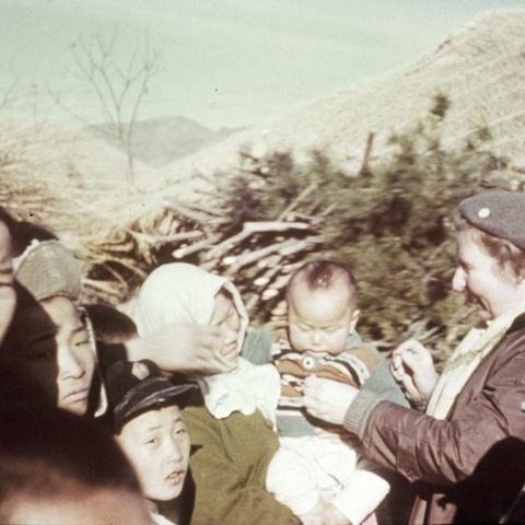 A Shelter For Kids worker with children and mothers in the aftermath of the Korean War.