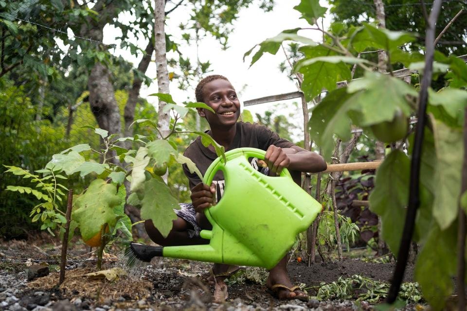 Charlie, 14, watering crops in a community nursery on an island in Shefa Province, Vanuatu.
