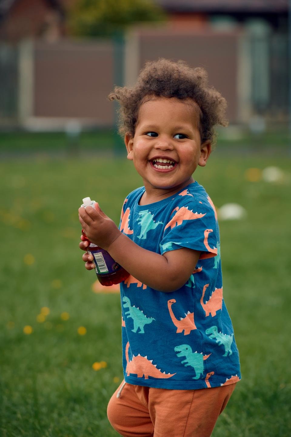 Malachi, one, laughs as he holds a bottle of juice, at 'Holiday Bites', Greater Manchester