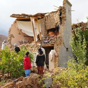 A family stands in front of their house damaged by the recent earthquake