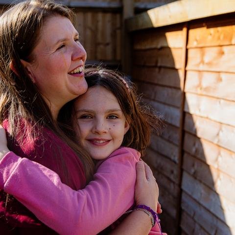 Sophie, nine & mum Mary hug one another, in their garden in Cardiff