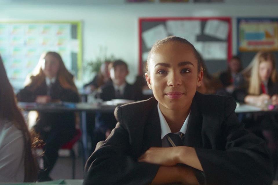 Girl in school uniform in a classroom sitting a desk