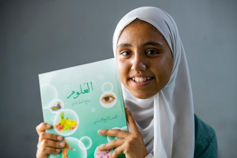 Portrait of Maram*, 14, holding her school notebook