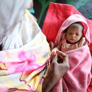 Newborn Sara*, 4 days old sleeping in her mother Asma's* arms at mobile clinic, Sudan